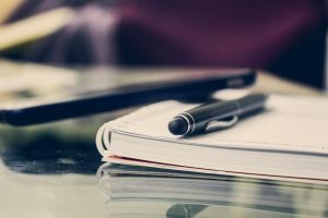 Close-up of an elegant pen resting on an open notebook in a stylish office environment.